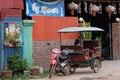 Little Asian girl sits in a moto rickshaw near a house with red lanterns