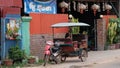 Little Asian girl sits in a moto rickshaw near a house with red lanterns