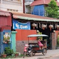 Little Asian girl sits in a moto rickshaw near a house with red lanterns