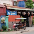 Little Asian girl sits in a moto rickshaw near a house with red lanterns