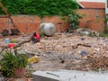 Man in a red shirt sitting on a pile of construction waste