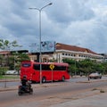 Red bus traveling along a city street, street traffic, cloudy evening