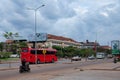 Red bus traveling along a city street, street traffic, cloudy evening