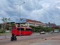 Red bus traveling along a city street, street traffic, cloudy evening