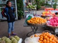 A young Asian girl sells fruit on a city street