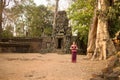 Happy Cambodian Asian Girl in Traditional Dress by an Ancient Temple Wall and Tree in Angkor Royalty Free Stock Photo