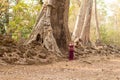 A Happy Smiling Cambodian Asian Girl in Traditional Dress Standing by an Old Tree in Angkor Thom Royalty Free Stock Photo