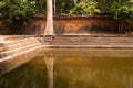 A Cambodian girl sitting by an ancient pool in Angkor Thom, Cambodia