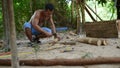 Cambodian man using axe to incise wooden beam