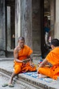 Cambodian monks sitting on stairs at Angkor Wat temple, Cambodia