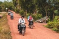 Cambodian people driving scooters through rural Cambodia