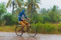 Cambodian person cycles while rain