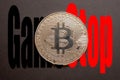 Cambridge UK January 2021Golden bitcoin coin on a black background, gamestop company logo overlaid behind. Gamestop stock pricee Royalty Free Stock Photo