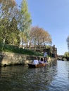 Cambridge, United Kingdom - April 20, 2019: People punting along the Cam river in Cambridge on a sunny day