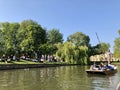 Cambridge, United Kingdom - April 20, 2019: People punting and chilling along the Cam river on a sunny day