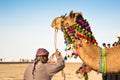 Camel herder owner stands near colorfully decorated camel in Gujarat India