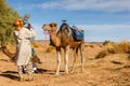 Camel looks at a man who drinks water Royalty Free Stock Photo