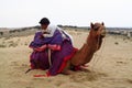 Camel with a man lying on the sand in the desert