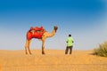 Camel owner with camel, Camelus dromedarius, while waiting for tourists at sand dunes of Thar desert. Camel riding is a Royalty Free Stock Photo