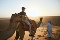 Camel riding in desert at sunset Royalty Free Stock Photo