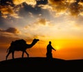 Cameleer camel driver with camels in desert dunes