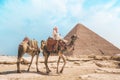 Camels with a local Bedouin walk through the desert near the Great Pyramid of Khufu in Giza near Cairo, Egypt