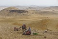 Camels wearing colorful saddle blankets wait for riders on sand covered with litter