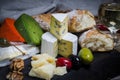 Mix cheese on dark background on wood board with grapes, honey, nuts, tomatoes and basil. Top view Royalty Free Stock Photo