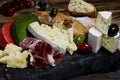 Mix cheese and meat on dark background on wood board with grapes, honey, nuts, tomatoes and basil. Top view. Royalty Free Stock Photo