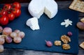 Camembert cheese on a black stone plate with tomatoes, crackers, nuts and grape Royalty Free Stock Photo