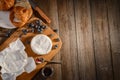 Camembert cheese, blueberries, jam and croissant on wooden background