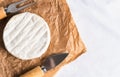 Camembert cheese, cheese knife and fork on craft paper on the table. Top view. Copy space. Close-up. Selective focus Royalty Free Stock Photo