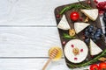 Camembert cheese with grapes, tomatoes cherry, pomegranate seeds, walnuts and rosemary on wooden cutting board Royalty Free Stock Photo