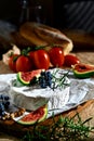 Camembert on parchment paper on wooden board close-up. The cheese is garnished with branch of grapes, wedge of figs and rosemary. Royalty Free Stock Photo