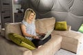 Camera approaching joyful positive Caucasian young beautiful woman sitting in apartment on sofa typing on laptop surfing Royalty Free Stock Photo