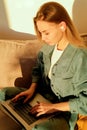 Camera approaching joyful young caucasian beautiful woman sitting in apartment on sofa typing on laptop surfing internet Royalty Free Stock Photo