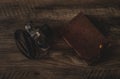 Camera and Brown, Tan Journal Lying on Top of a Wooden Textured Background