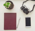 Camera, burgundy notepad, pen, green flower and mobile smart phone view from above. Royalty Free Stock Photo