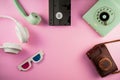 Camera, 3D glasses, VHS videotape. Rotary phone, telephone handset, white headphones, brown leather camera case on pink Royalty Free Stock Photo