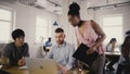 Camera follows African American woman boss enter office, give directions to workers. Multiethnic group teamwork 4K.