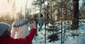 Camera follows happy multiethnic friends walk on sunny snowy winter forest path on Christmas weekend hike slow motion.