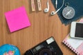 Camera, Globes, headphones, compass, phone, Notebook , Sticky note on the wooden desk.