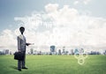 Camera headed man standing on green grass against modern cityscape