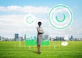 Camera headed woman standing on green grass against modern cityscape