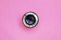 Camera lens with a closed aperture lie on texture background of fashion pastel pink color paper in minimal concept