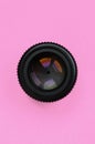 Camera lens with a closed aperture lie on texture background of fashion pastel pink color paper in minimal concept