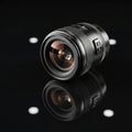 Camera lens placed on a reflective black surface, creating a Royalty Free Stock Photo