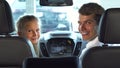 Funny dad with his daughter sit in the front seats and look at the small screen of the car Royalty Free Stock Photo