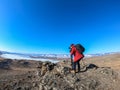 Camera man in orange winter jacket takes landscape photo of Baikal lake in Russia