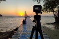 Camera mounted on a tripod photograph man and woman on the pier and sunrise Royalty Free Stock Photo